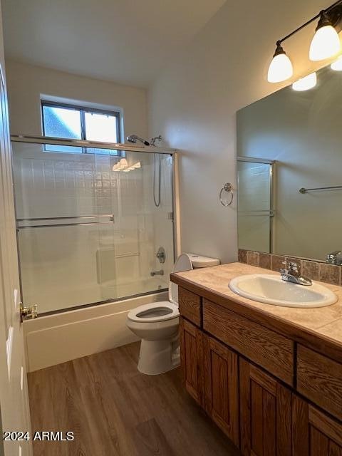 full bathroom featuring enclosed tub / shower combo, wood-type flooring, vanity, and toilet