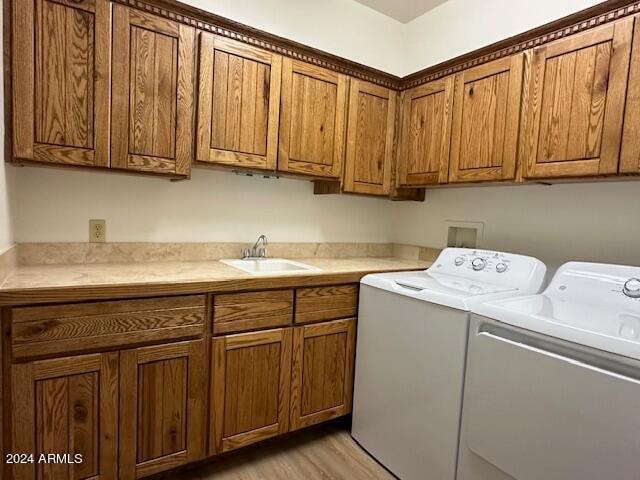 laundry room featuring cabinets, light wood-type flooring, sink, and washer and clothes dryer