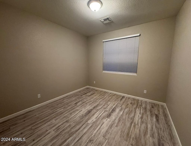 empty room with hardwood / wood-style flooring and a textured ceiling