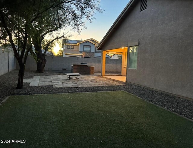 yard at dusk featuring a patio area