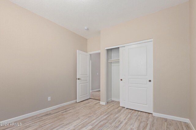 unfurnished bedroom with light wood-type flooring and a closet