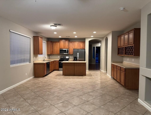 kitchen with sink, a kitchen island, stainless steel appliances, and light tile patterned floors