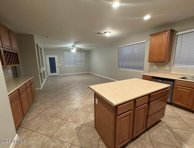 kitchen featuring stainless steel dishwasher, ceiling fan, sink, light tile patterned floors, and a center island