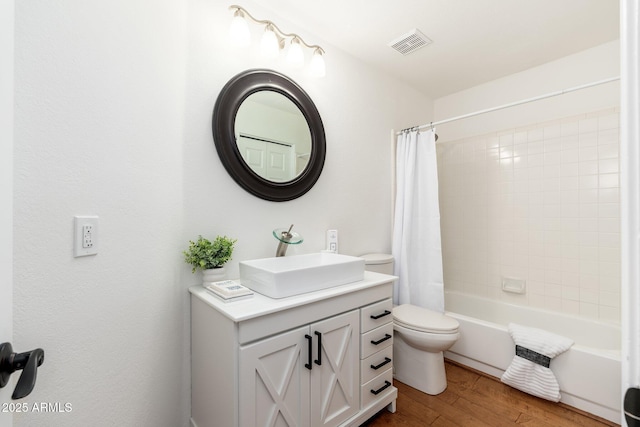 bathroom with toilet, wood finished floors, vanity, visible vents, and shower / tub combo with curtain