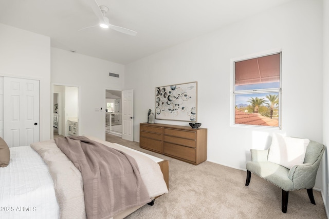 bedroom with ceiling fan, visible vents, ensuite bathroom, and light colored carpet