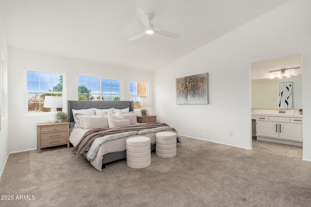 bedroom featuring light carpet, baseboards, lofted ceiling, ensuite bathroom, and a sink