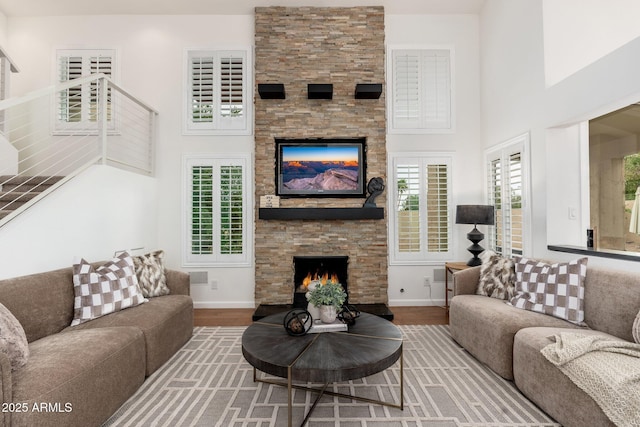 living room with wood finished floors, a fireplace, a towering ceiling, and a wealth of natural light