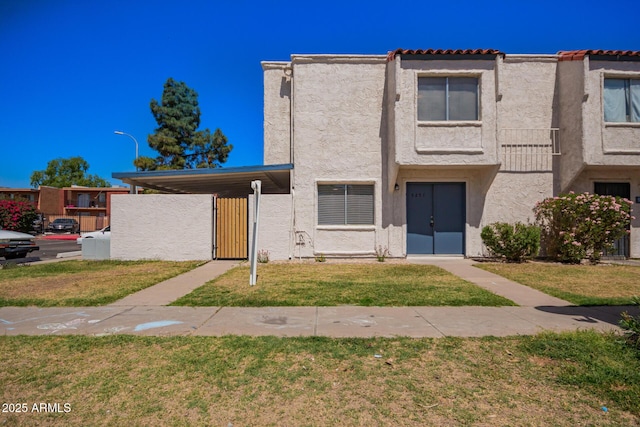 view of property with a front lawn, a gate, and stucco siding