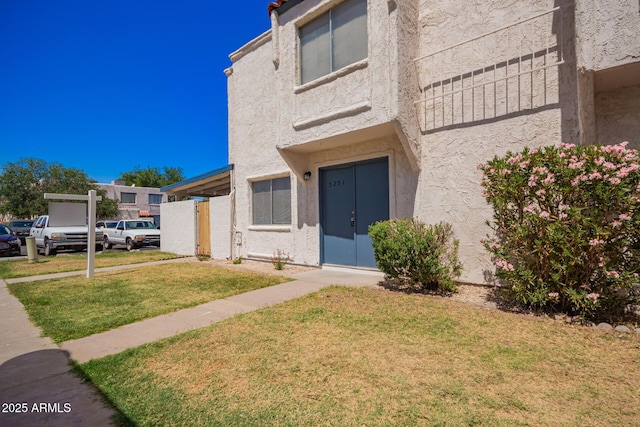 doorway to property with a lawn and stucco siding