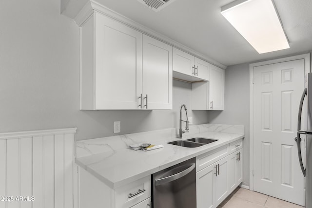 kitchen with stainless steel dishwasher, white cabinetry, a sink, and light stone counters