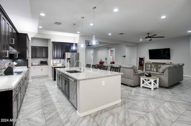 kitchen with sink, stainless steel appliances, a kitchen island with sink, and hanging light fixtures