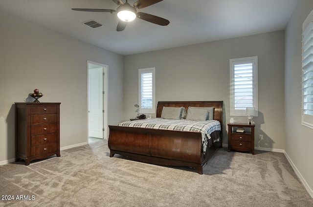 bedroom with multiple windows, ceiling fan, and light colored carpet