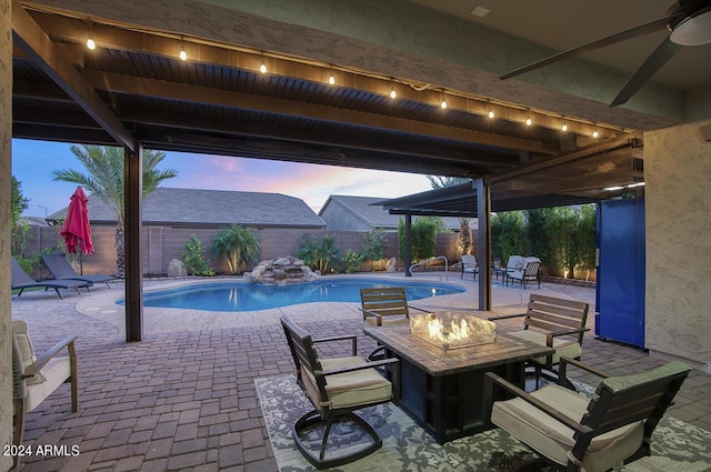 patio terrace at dusk featuring a fenced in pool and a fire pit