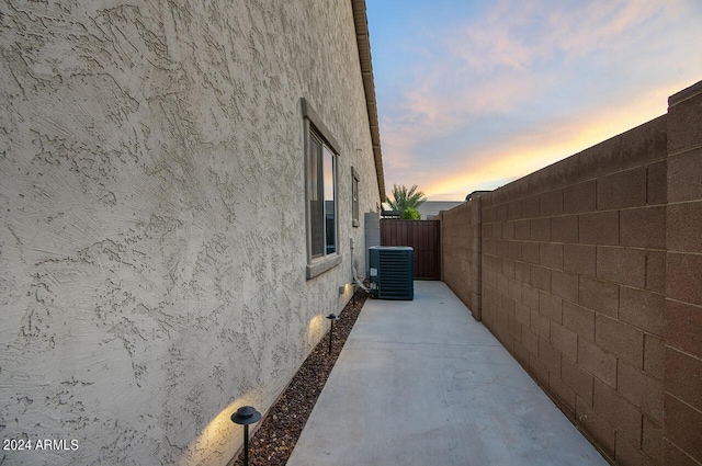 property exterior at dusk with central air condition unit and a patio area