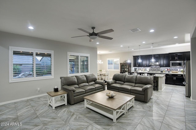 living room with ceiling fan with notable chandelier