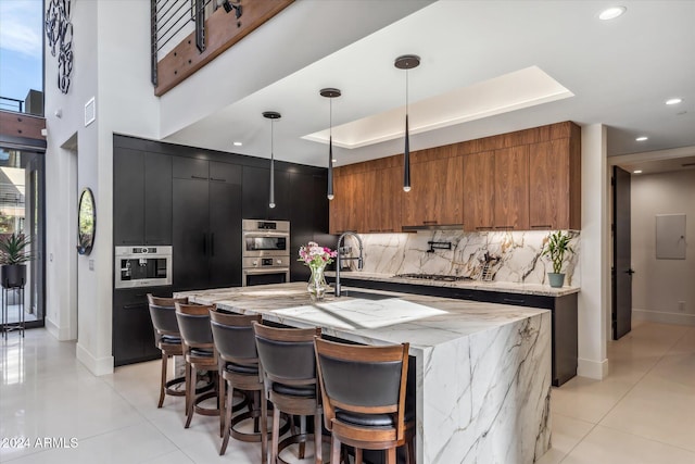 kitchen with a large island, sink, decorative light fixtures, decorative backsplash, and appliances with stainless steel finishes