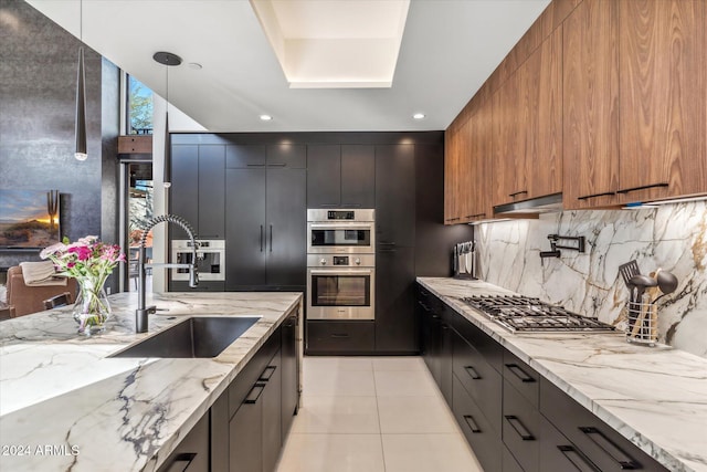 kitchen with light stone countertops, backsplash, stainless steel appliances, and sink