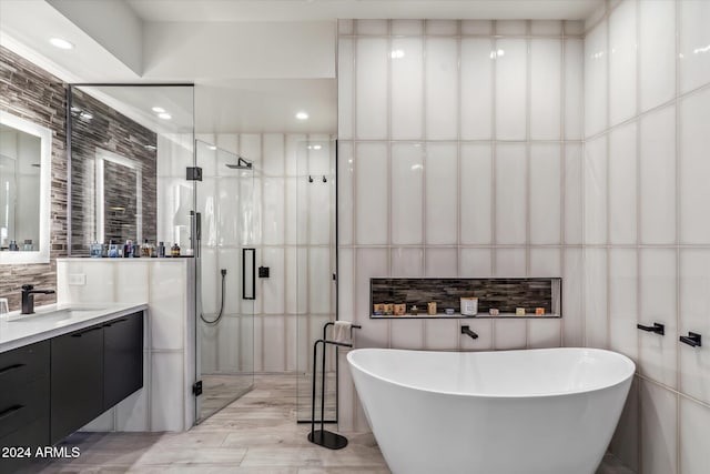 bathroom with vanity, wood-type flooring, tile walls, and independent shower and bath