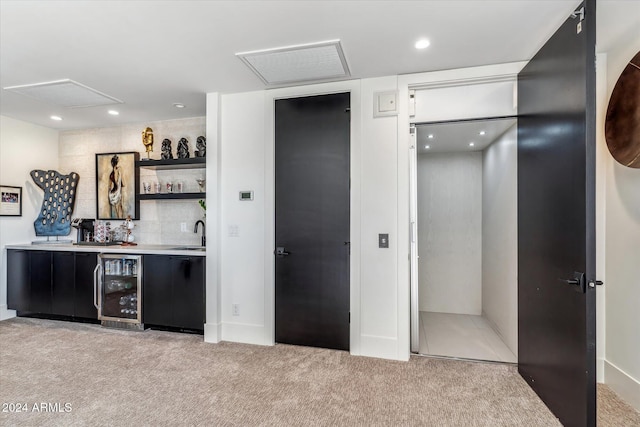 bar with light carpet, beverage cooler, and sink