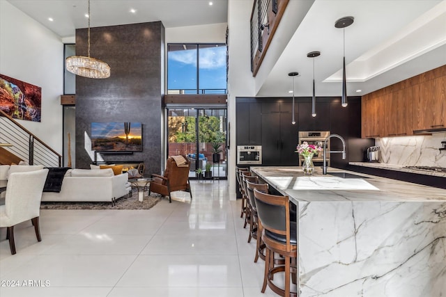 kitchen with backsplash, a breakfast bar, decorative light fixtures, and sink