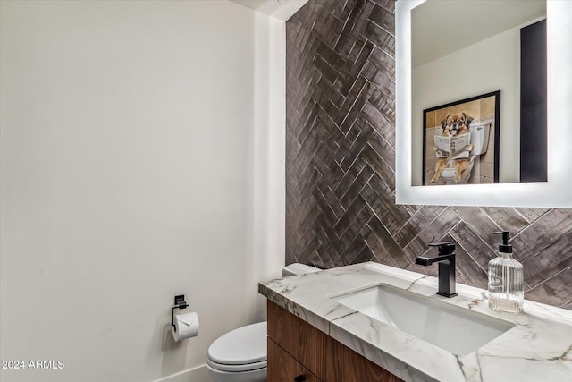 bathroom featuring vanity, toilet, and backsplash