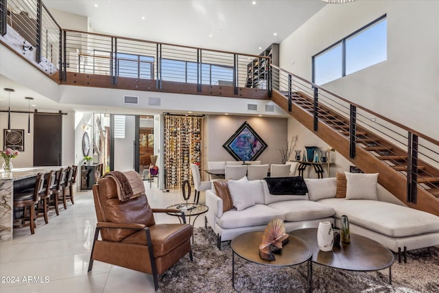 living room with a barn door, a towering ceiling, and light tile patterned flooring