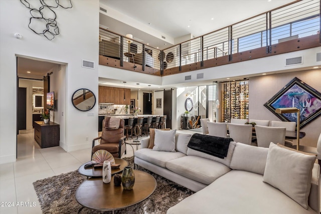 living room with a towering ceiling and light tile patterned floors