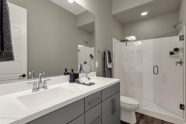 bathroom featuring toilet, a stall shower, wood finished floors, and vanity