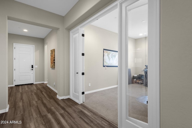 hallway featuring dark wood finished floors and baseboards