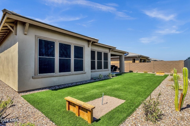 rear view of house featuring stucco siding, a fenced backyard, and a yard