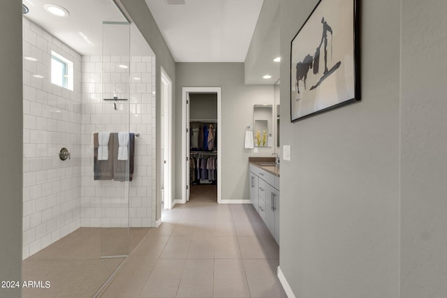 bathroom with baseboards, tile patterned floors, a walk in closet, vanity, and a walk in shower