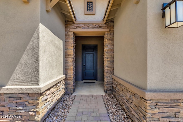 doorway to property with stone siding and stucco siding