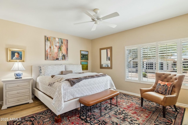 bedroom with light wood finished floors, baseboards, and ceiling fan