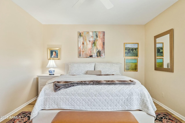 bedroom featuring a ceiling fan, baseboards, and wood finished floors