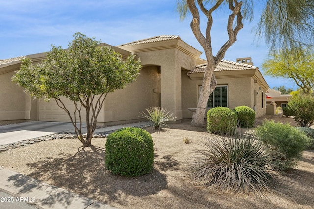 view of front facade featuring stucco siding, a tiled roof, a garage, and concrete driveway
