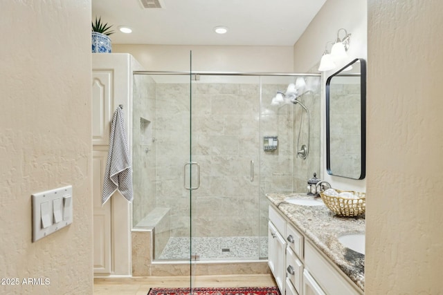 bathroom with a shower stall, double vanity, visible vents, and a sink