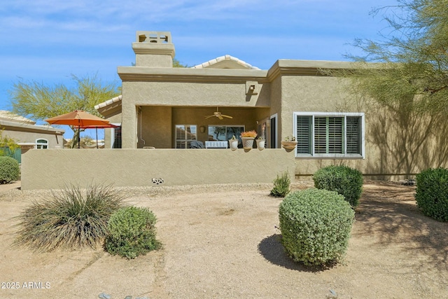 rear view of property featuring stucco siding, a chimney, and a fenced front yard