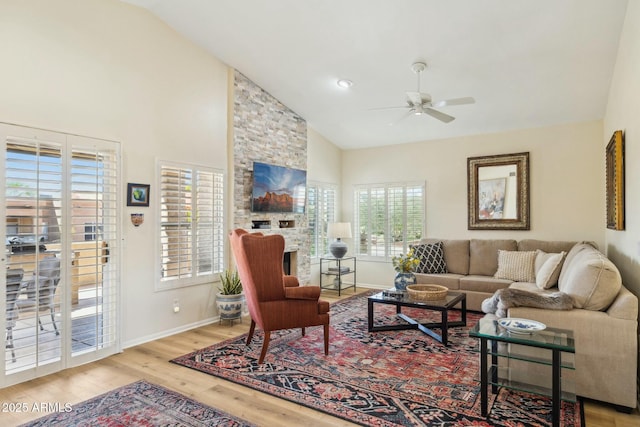 living area featuring a ceiling fan, high vaulted ceiling, baseboards, and wood finished floors