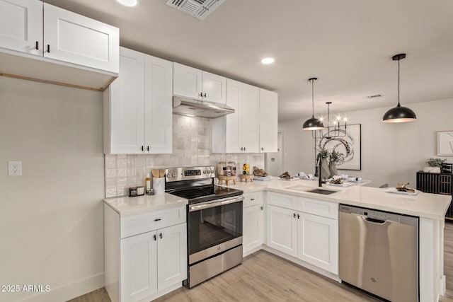 kitchen with kitchen peninsula, appliances with stainless steel finishes, decorative light fixtures, and white cabinets