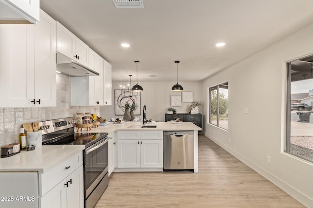 kitchen featuring white cabinetry, sink, stainless steel appliances, kitchen peninsula, and decorative light fixtures