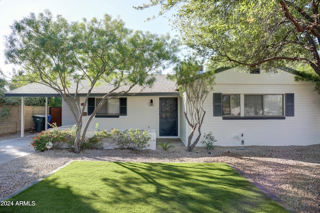 ranch-style home featuring a shingled roof, fence, and a front lawn