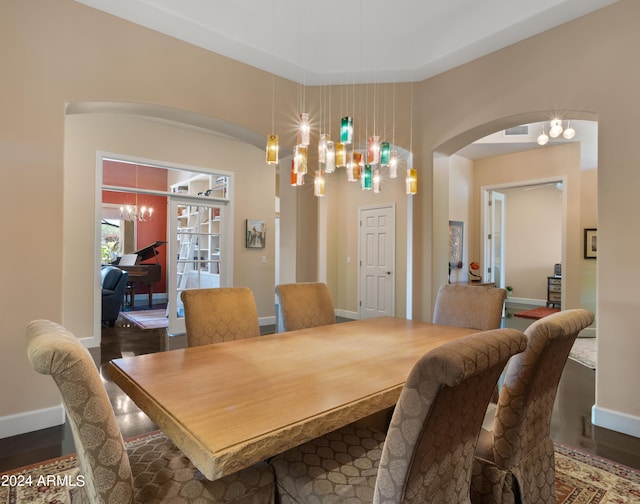 dining space featuring dark wood-type flooring and a notable chandelier