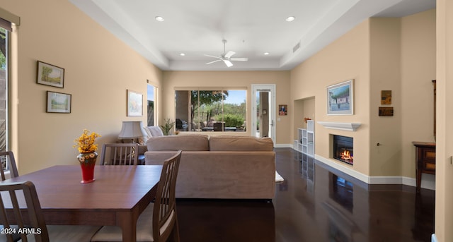 living room with a raised ceiling and ceiling fan