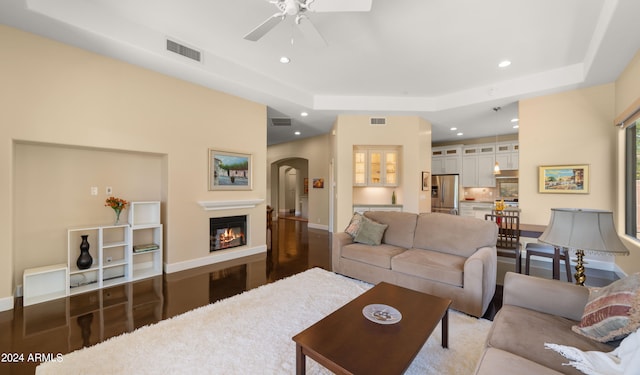 living room featuring a raised ceiling and ceiling fan