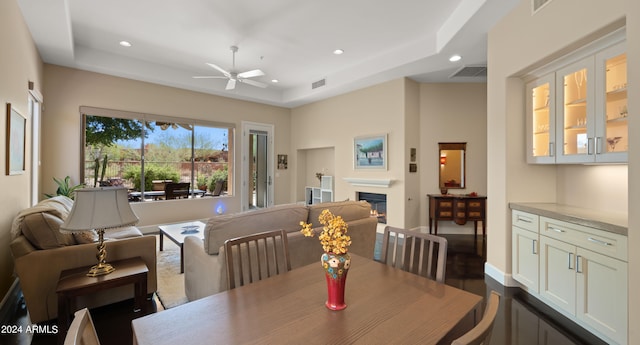 dining room with ceiling fan and a tray ceiling