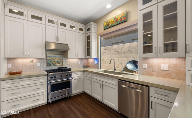 kitchen with appliances with stainless steel finishes, backsplash, dark wood-type flooring, sink, and white cabinets