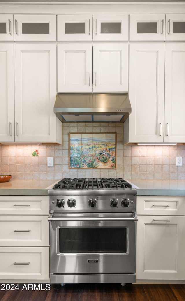 kitchen featuring tasteful backsplash, designer stove, extractor fan, and white cabinetry