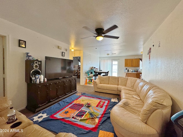 carpeted living room featuring ceiling fan and a textured ceiling