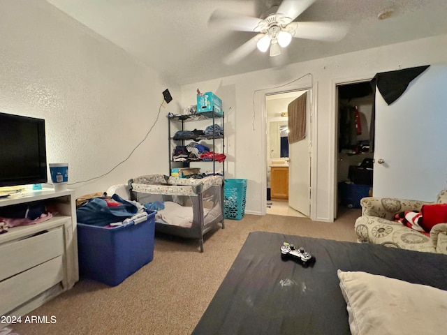 bedroom with light carpet, ceiling fan, and ensuite bath