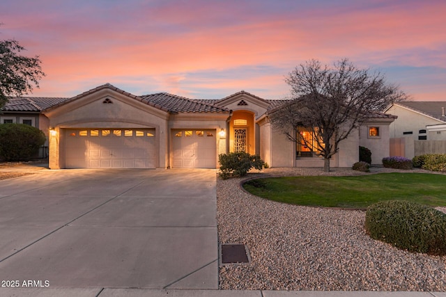 mediterranean / spanish-style home with a garage, driveway, a tile roof, fence, and stucco siding